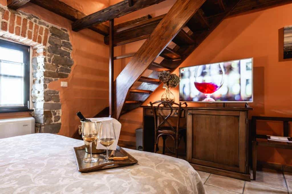 Wine chilling in bucket with glasses on bed next to wooden staircase in rustic room