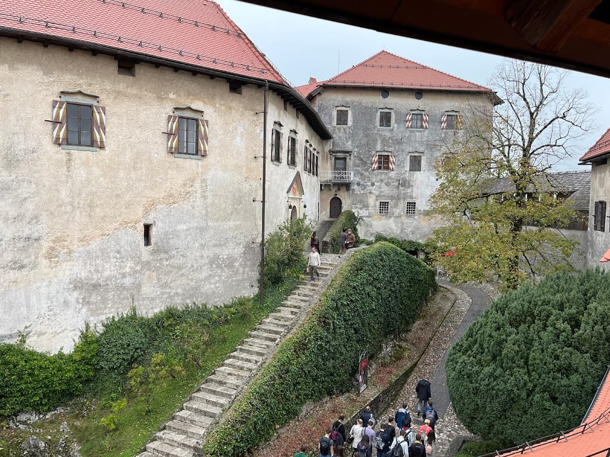 Stone staircase and courtyard between old buildings with red roofs, tourists walking below