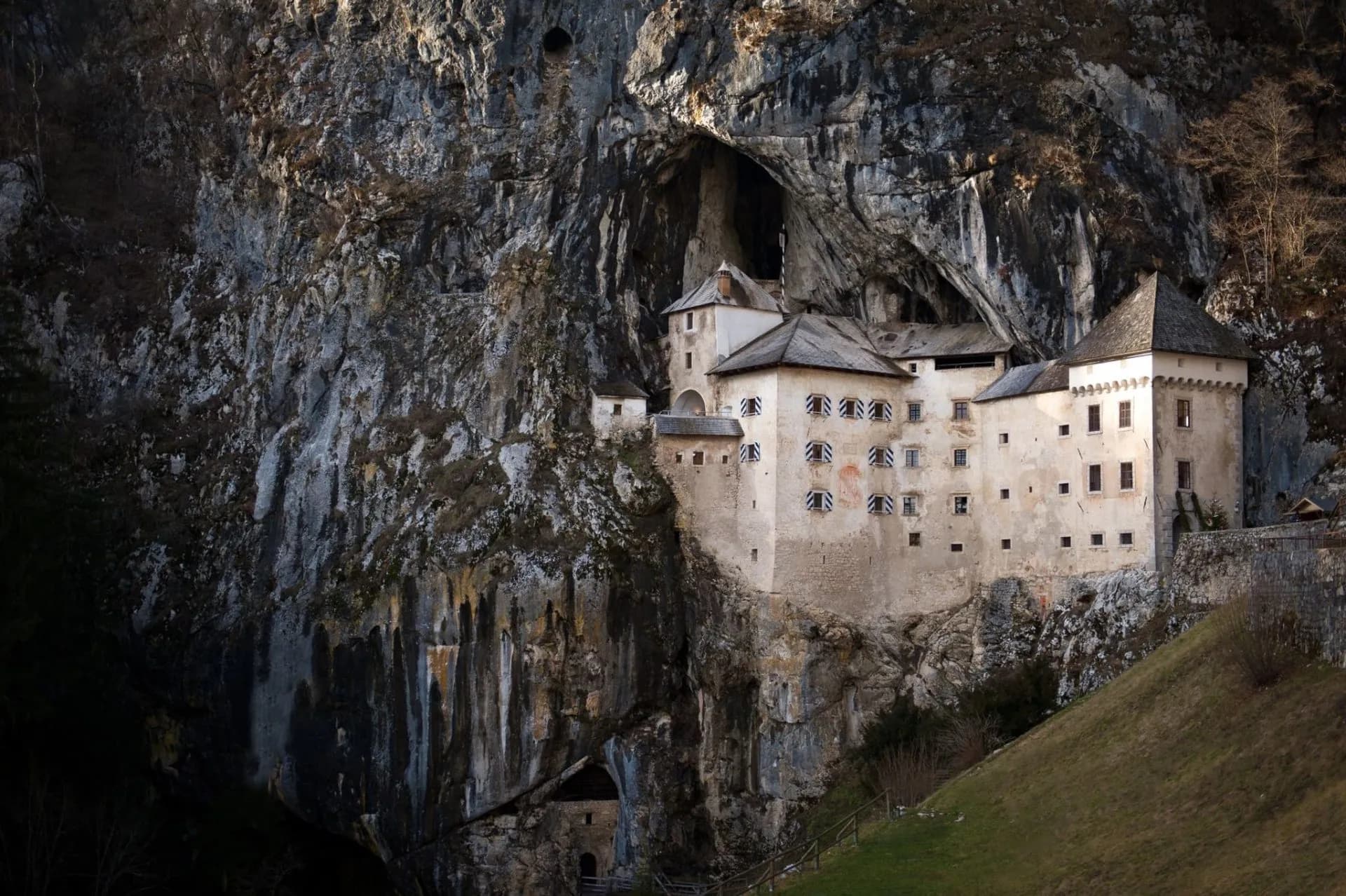 Castle built into a massive cliff face with a large cave entrance above it