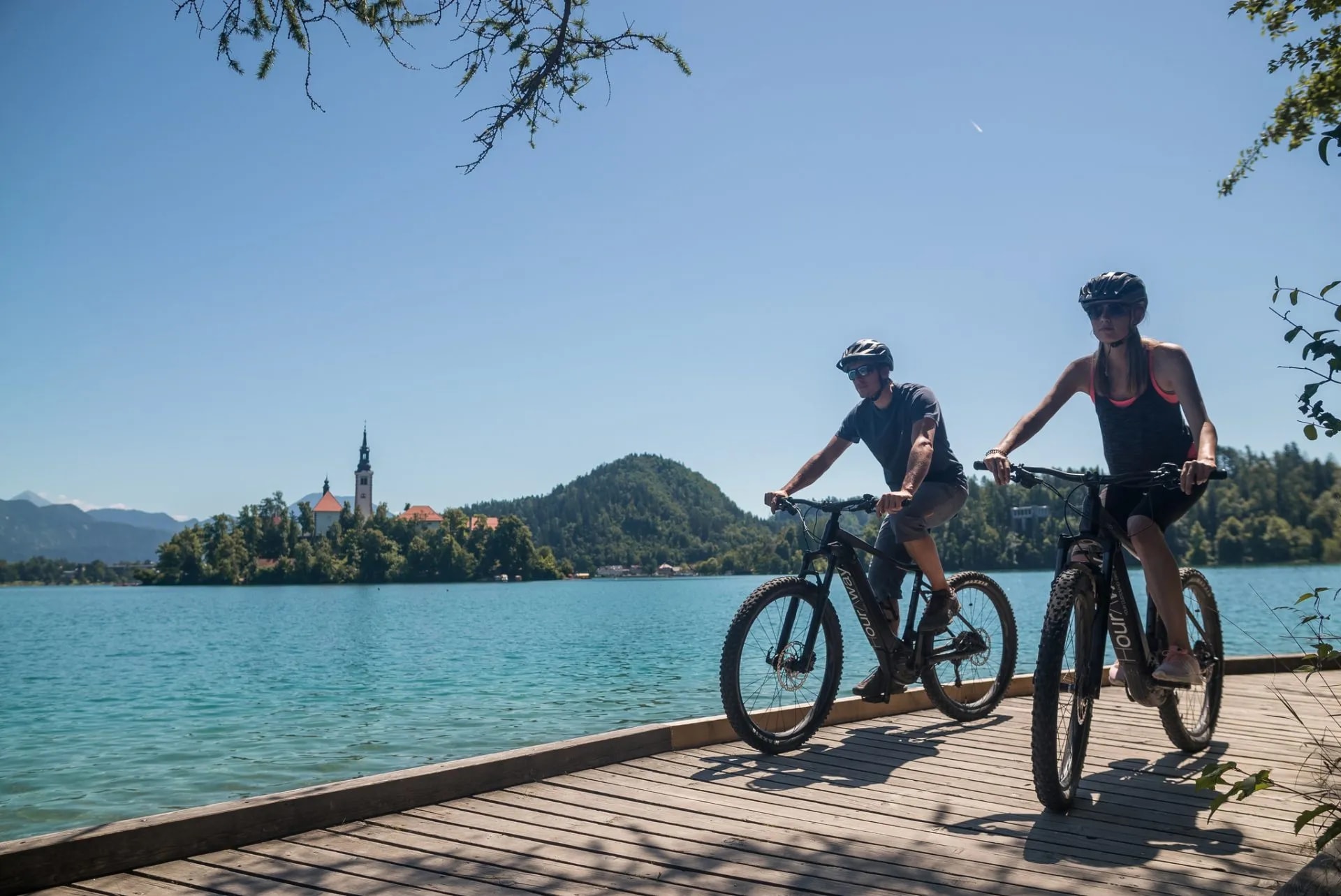 Cycling by Lake Bled with the island church and mountains in the background.
