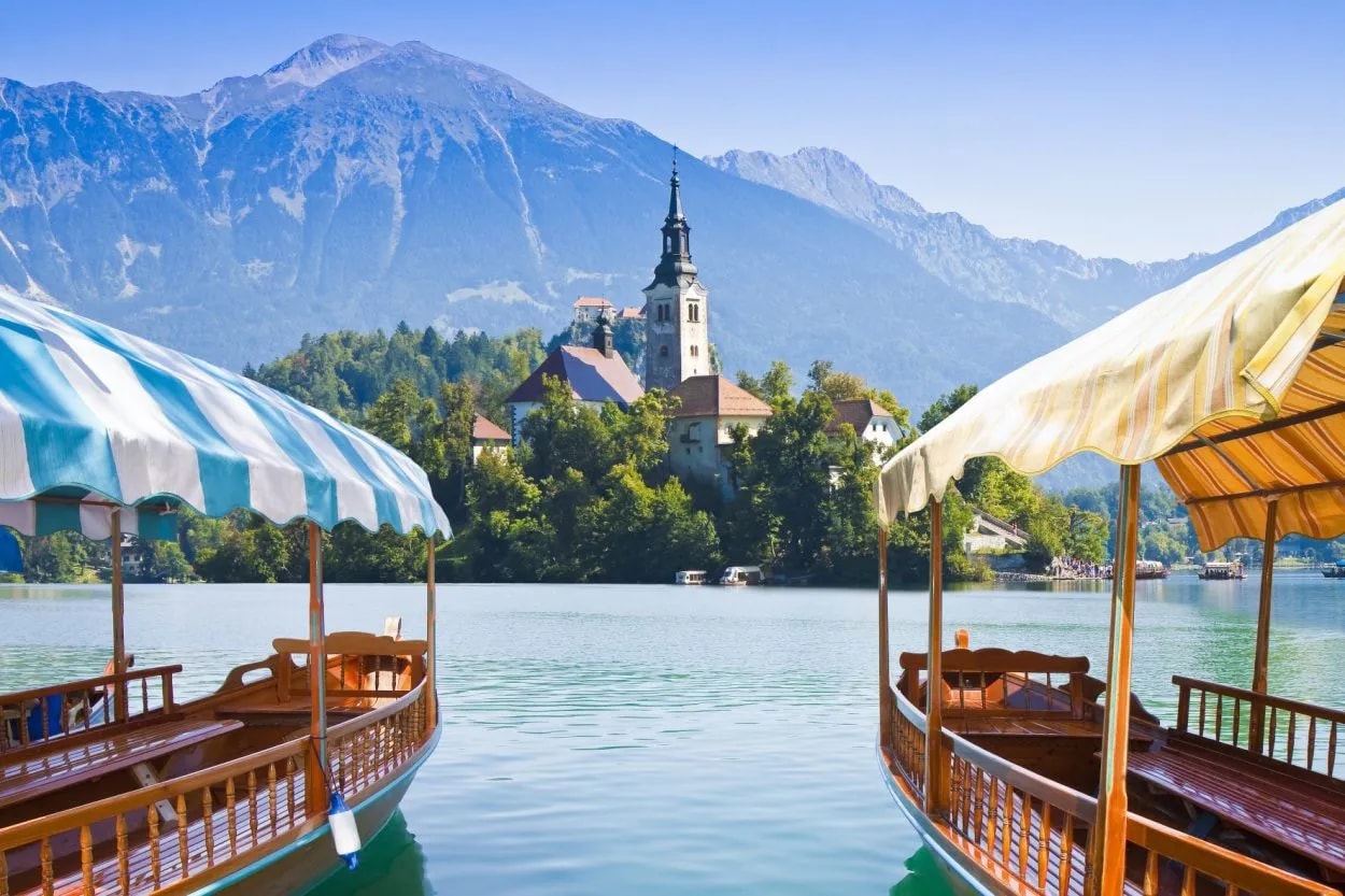 Pletna boats on Lake Bled with island church and Julian Alps in background
